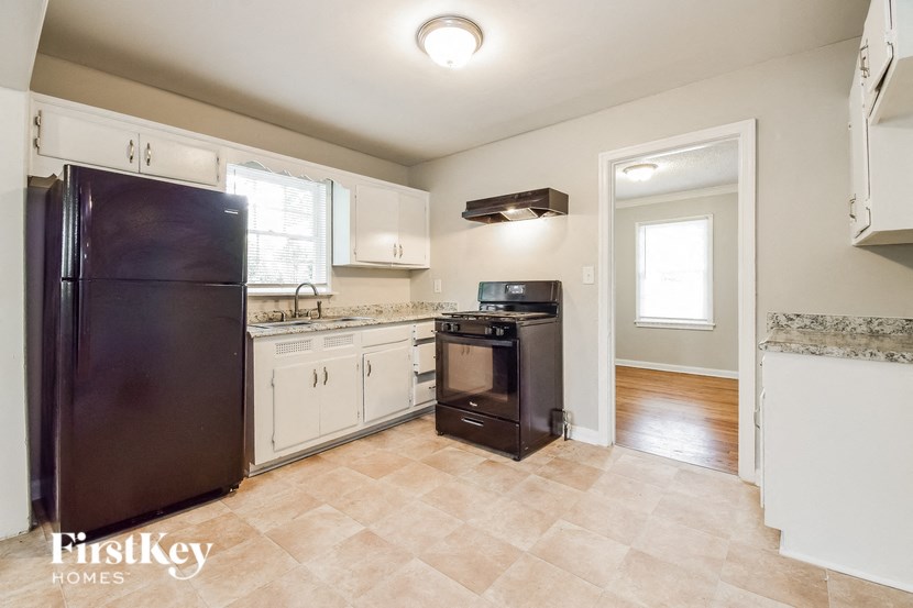a kitchen with white cabinets and a black refrigerator