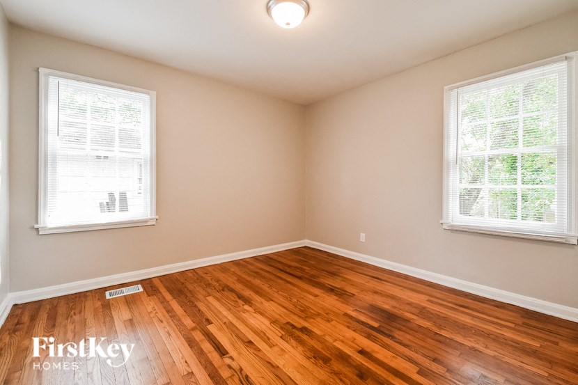 an empty room with wood floors and two windows