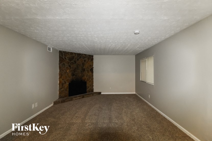 a carpeted living room with a fireplace and gray walls