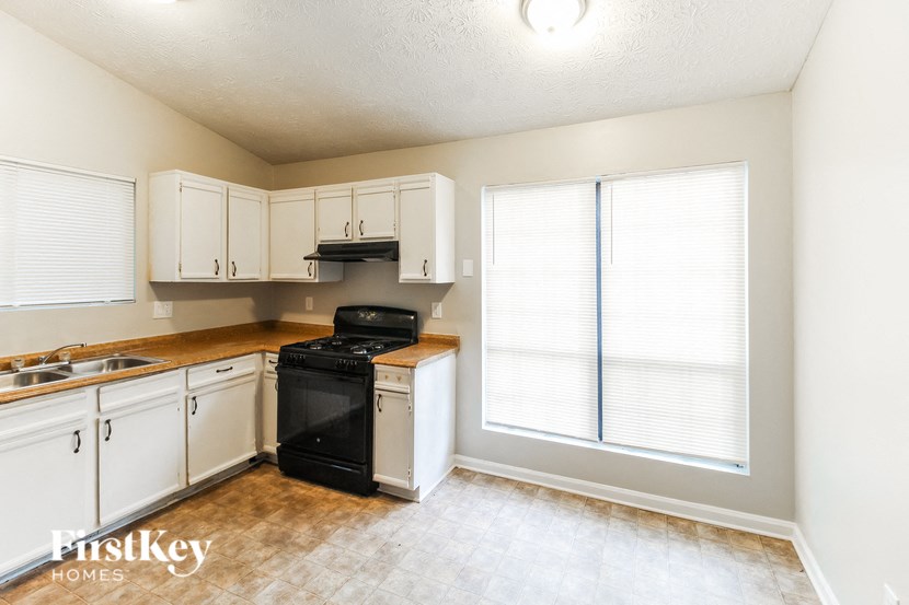 a kitchen with white cabinets and a black stove and a window