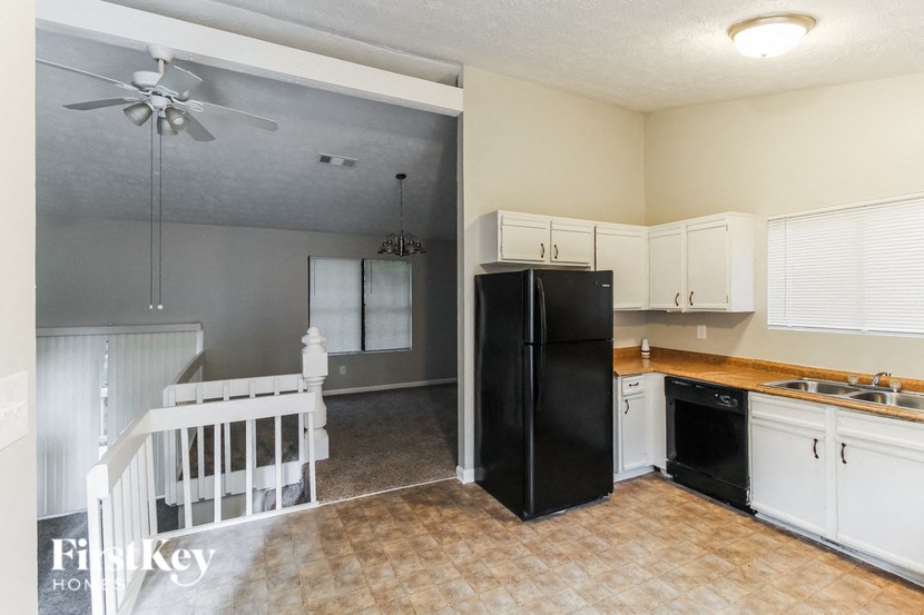 a kitchen with a baby crib and a black refrigerator