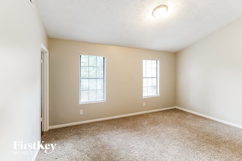 an empty room with carpet and two windows