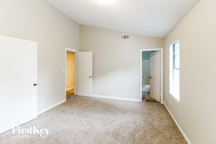 a spacious living room with carpet and a door to a bathroom