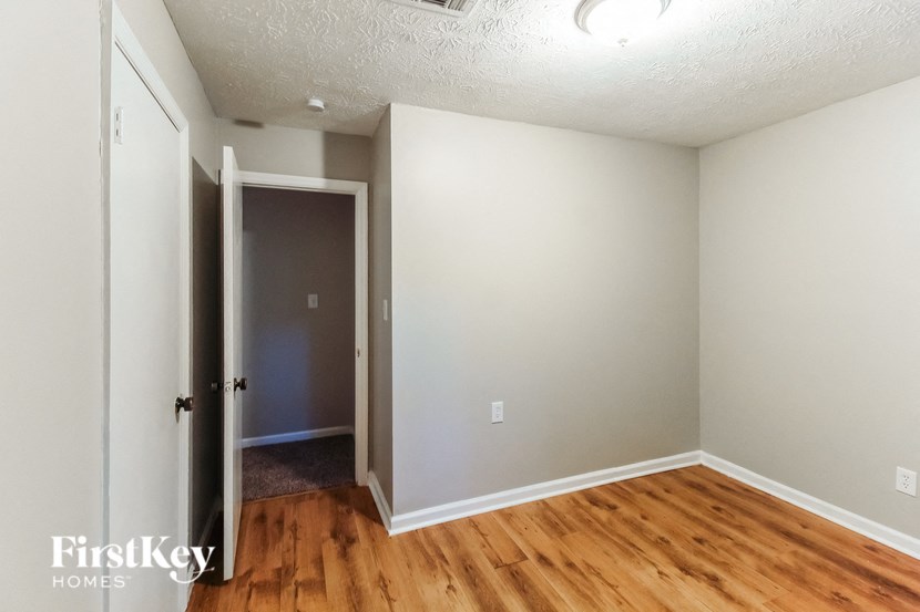 a bedroom with a hard wood floor and a door to a closet