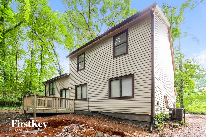 the back of a house with a wooden deck and trees