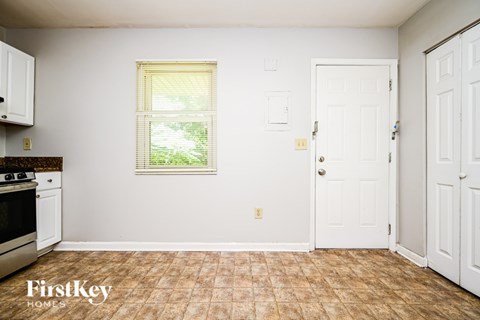 A kitchen with a stove top oven and a window with blinds.