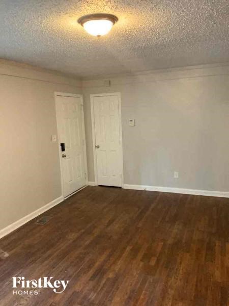 an empty living room with a wooden floor and a white door