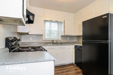 A kitchen with a black refrigerator and a granite counter top.