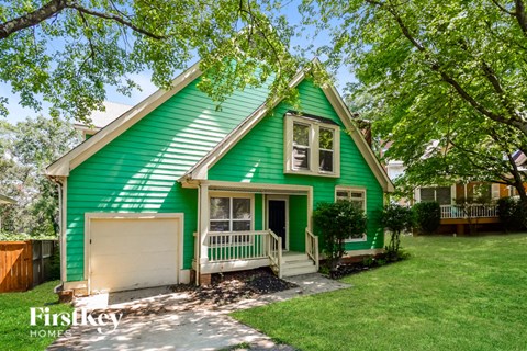 a green house with a green yard and a white garage door