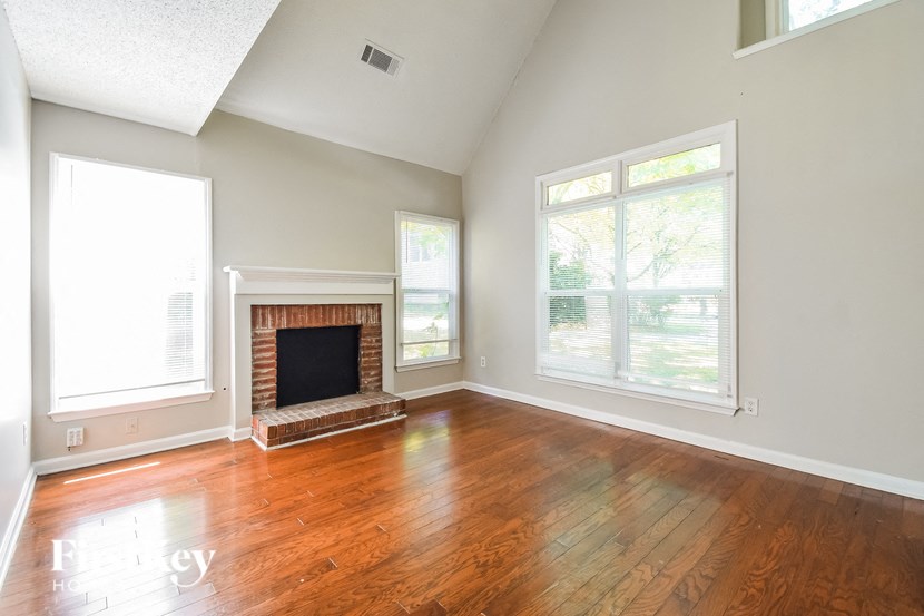 an empty living room with wood floors and a fireplace