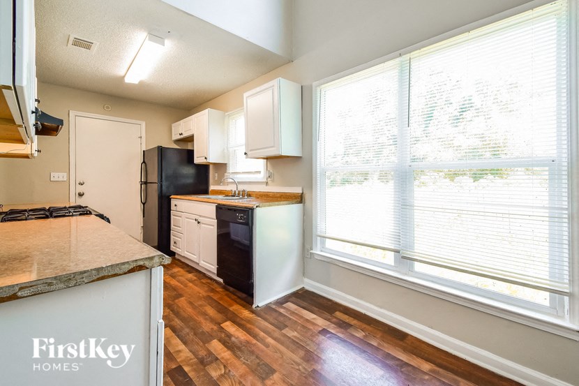 a kitchen with white cabinets and black appliances and a large window