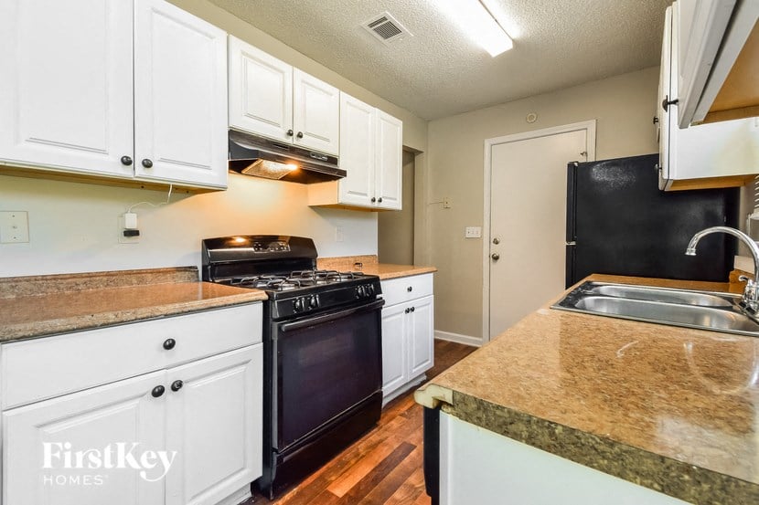 a kitchen with white cabinets and a black stove and a sink