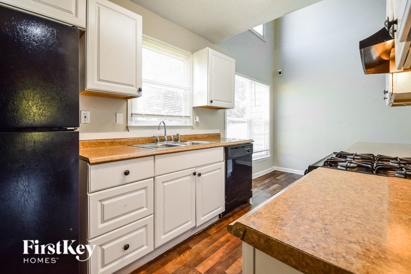 a kitchen with white cabinets and black appliances and a counter top