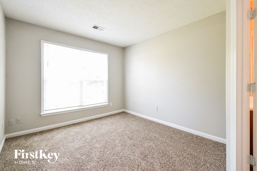 a bedroom with carpet and a large window