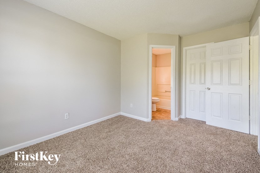 a bedroom with a carpeted floor and a door to a bathroom