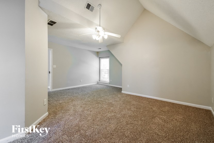 an empty living room with carpet and a ceiling fan