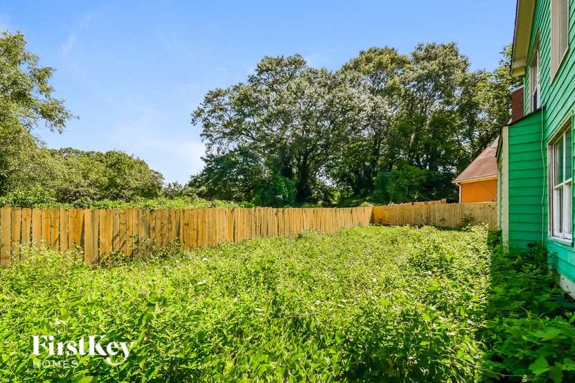 a backyard with a wooden fence and a green house