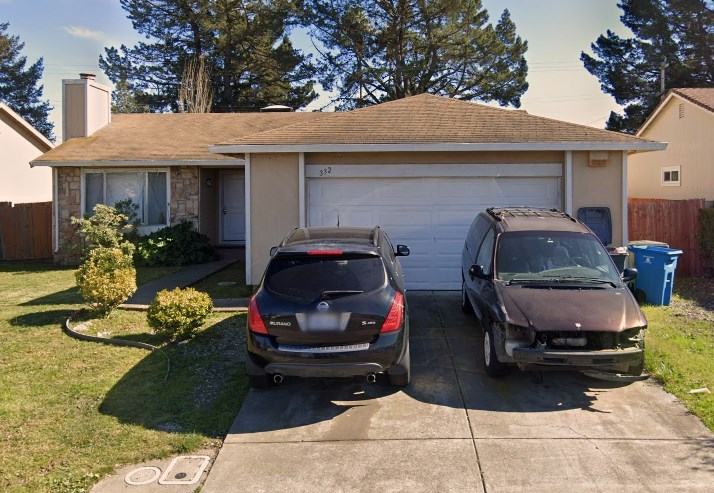 Two cars are parked in front of a house.