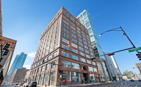 A tall building with many windows is in the middle of a city street.