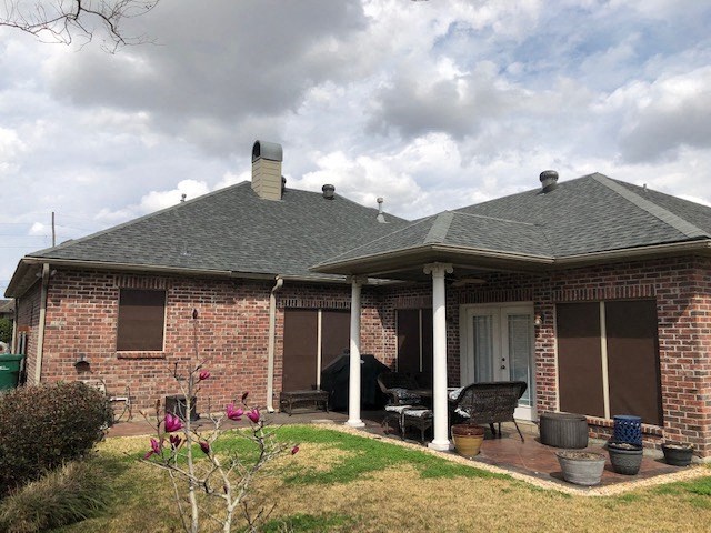 a brick house with a porch and a cloudy sky