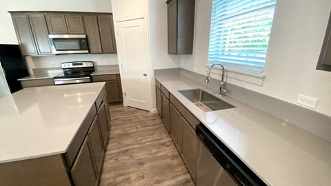 A kitchen with brown cabinets and a black dishwasher.