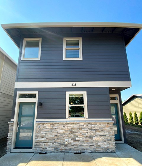 A two-story house with a stone wall at the entrance.