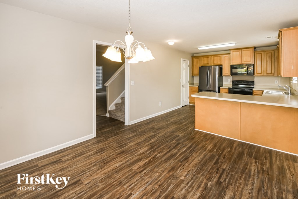 a living room with wood flooring and a kitchen with wood cabinets