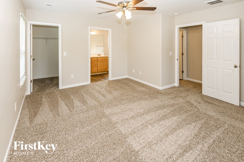 an empty living room with carpet and a ceiling fan