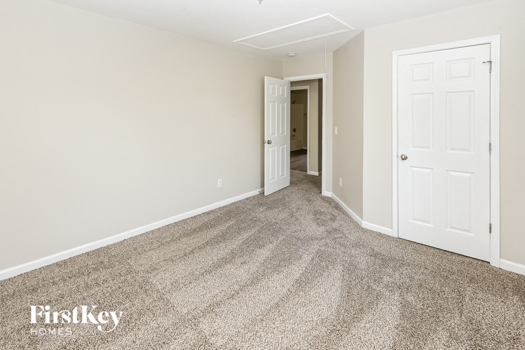 a bedroom with a carpeted floor and a white door