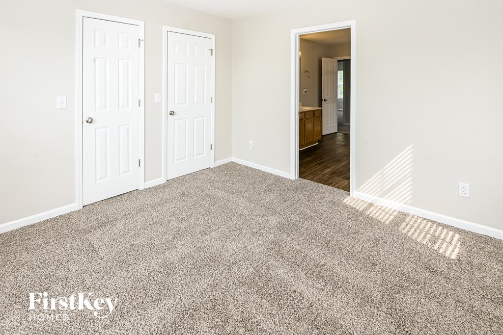 an empty room with a carpeted floor and a door to a bedroom