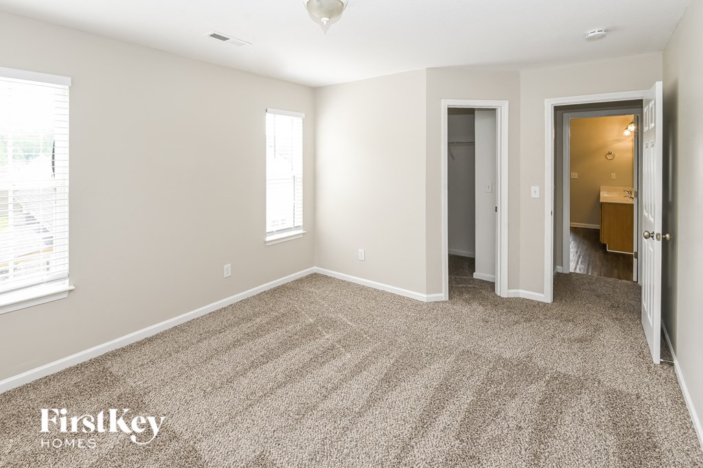 a spacious living room with carpet and a door to a bathroom