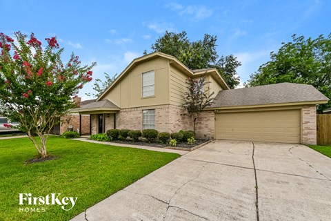 a beige house with a driveway and a lawn