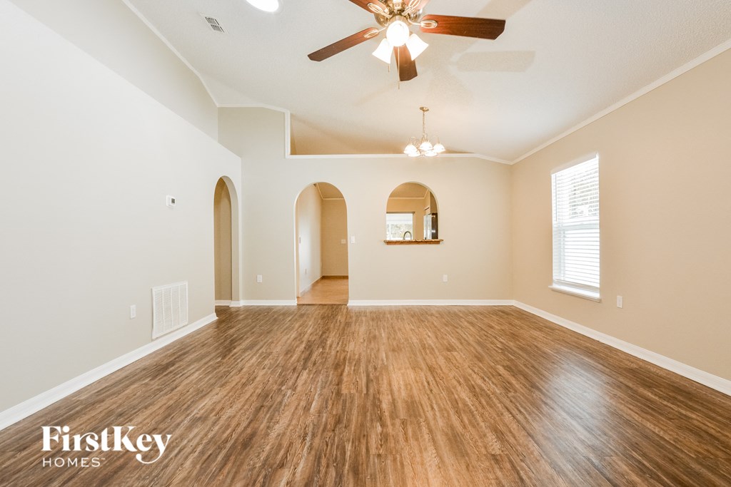 the spacious living room with hardwood floors and a ceiling fan