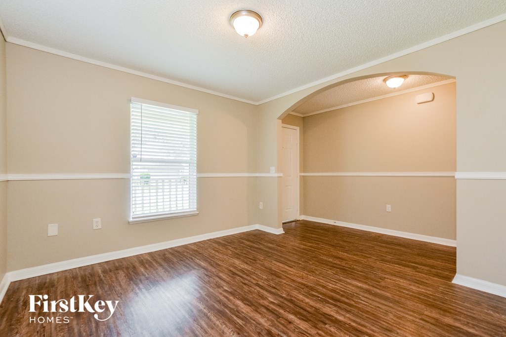 an empty living room with a hardwood floor and a window