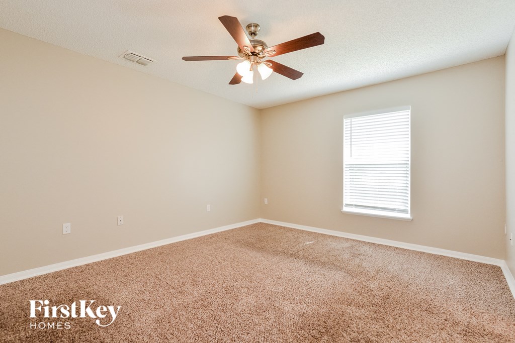 the master bedroom has a ceiling fan and a carpeted floor