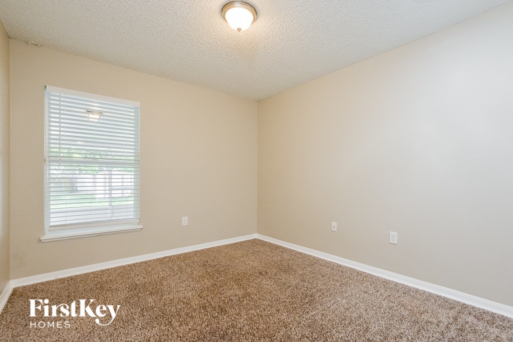 the spacious bedroom with carpeted flooring and a window