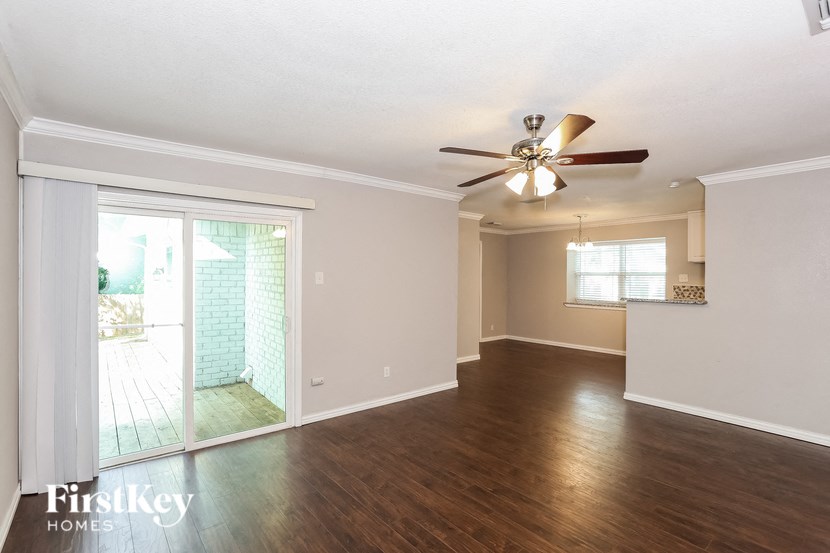 an empty living room with a ceiling fan and a sliding glass door