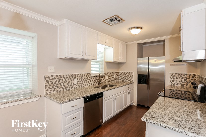 a kitchen with white cabinets and granite counter tops and a stainless steel refrigerator
