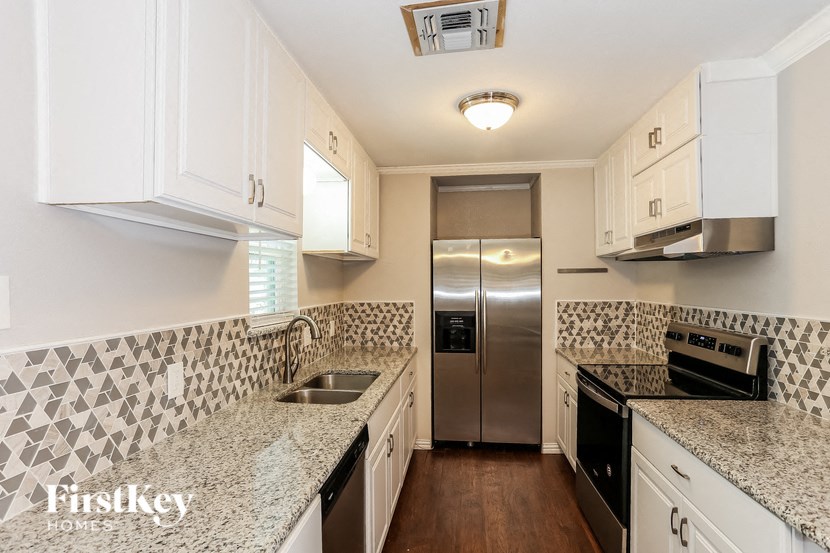 a kitchen with granite counter tops and a stainless steel refrigerator