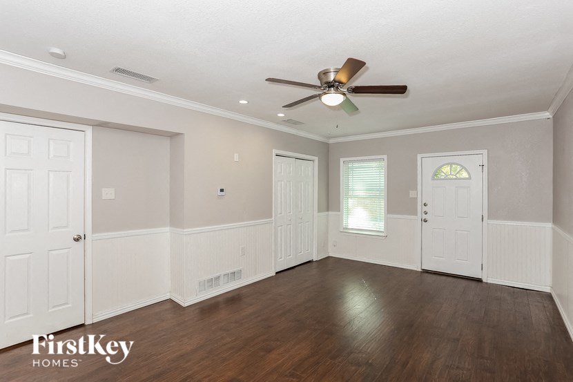 an empty living room with a ceiling fan and white walls