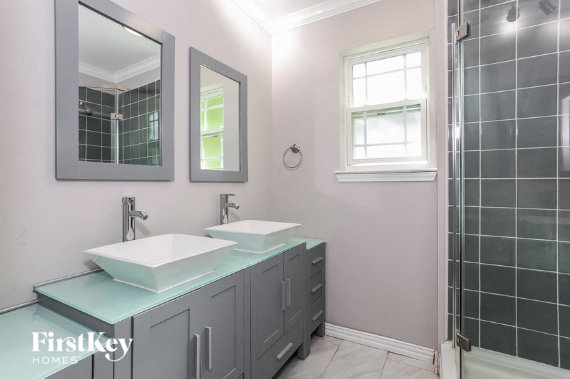 a bathroom with two sinks and a shower and two mirrors