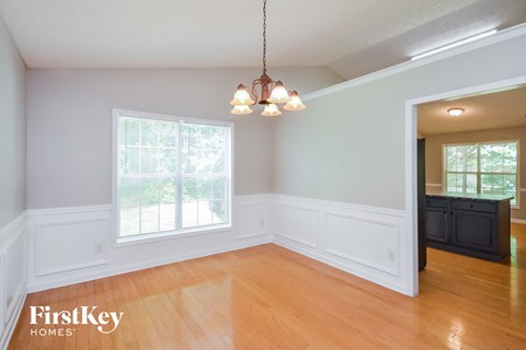 an empty dining room with wood floors and a chandelier