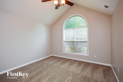the living room of a home with an arched window and carpet