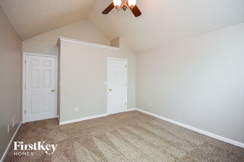 a bedroom with carpet and white doors and a ceiling fan