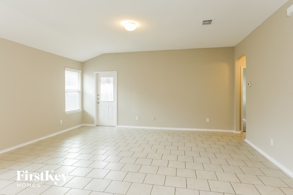 an empty living room with a white tile floor and a door