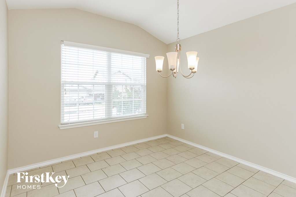 a dining room with a large window and a tiled floor