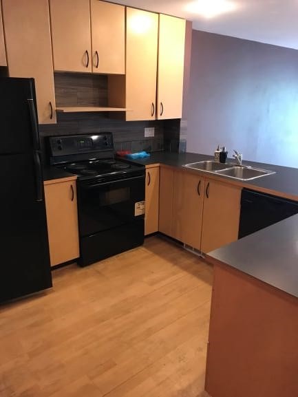 A kitchen with black appliances and wooden cabinets.
