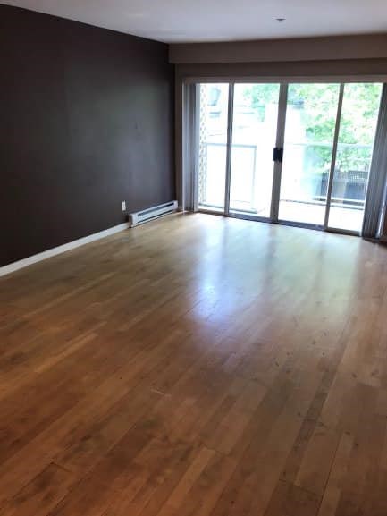 A room with wooden flooring and sliding glass doors.