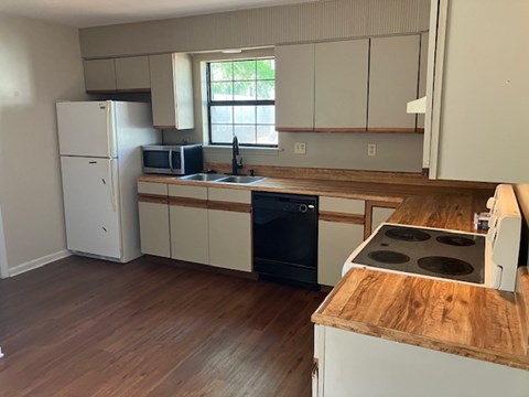 A kitchen with a white fridge, black dishwasher, and wooden countertops.