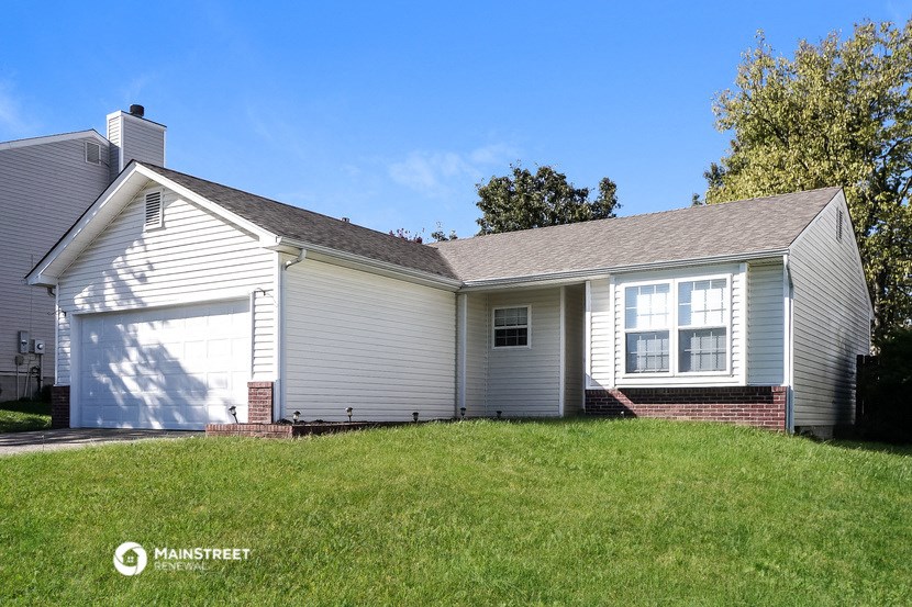 the front of a white house with a garage and a lawn